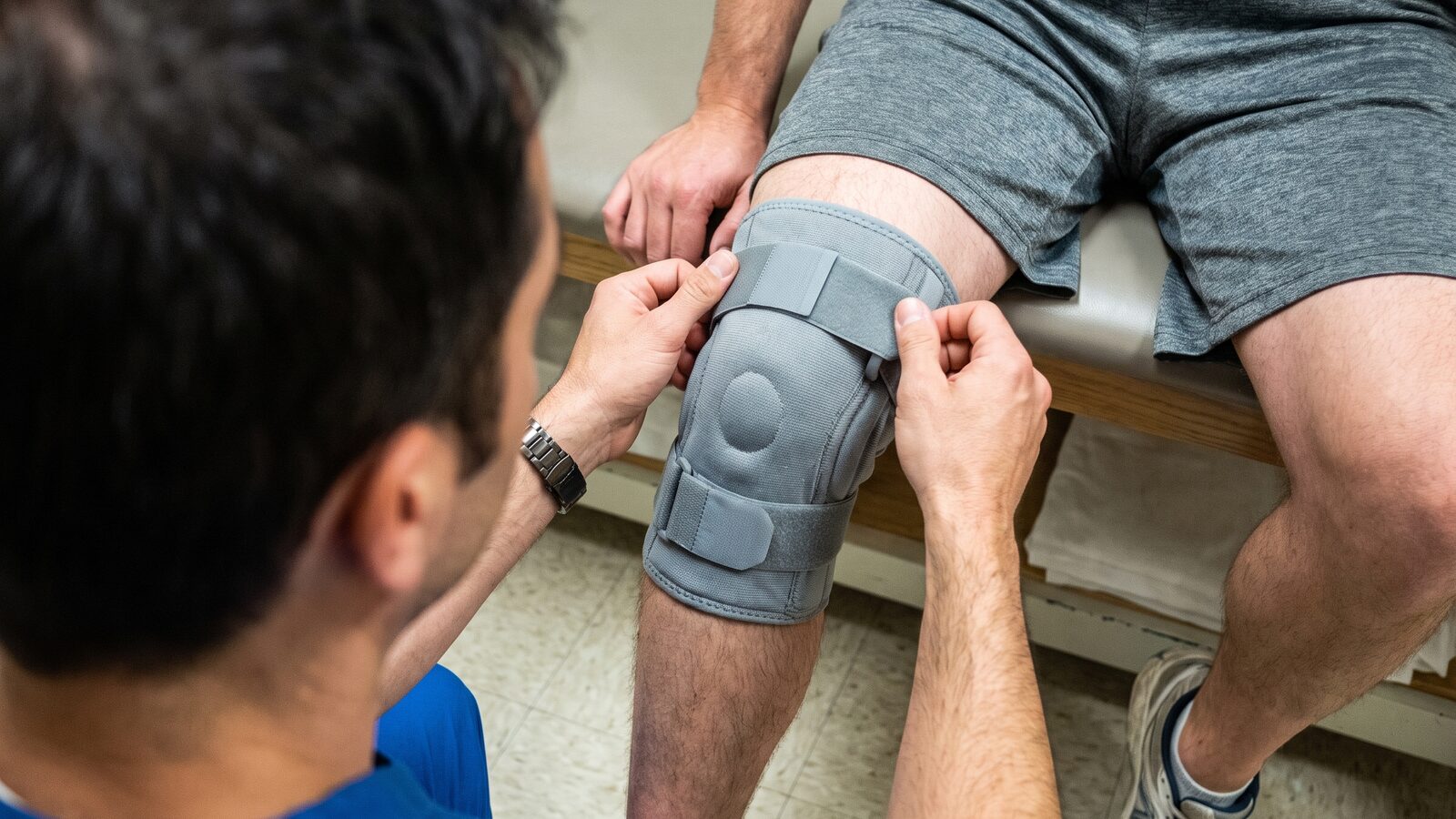 A physical therapist fitting a knee brace on a patient during recovery in a Phoenix clinic